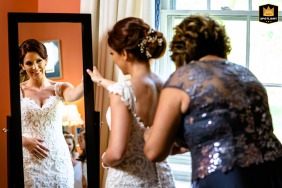 At Radnor Hunt in Philadelphia, the mother of the bride adjusts her daughter’s gown, her happiness shining brightly in the reflective surface of the mirror.
